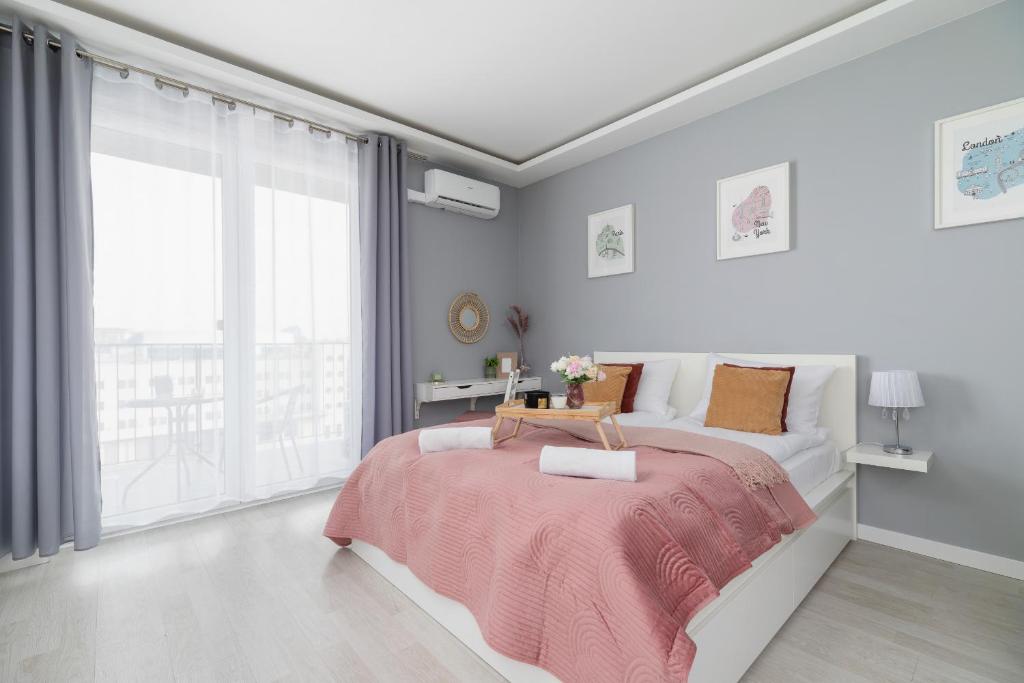 a white bedroom with a large bed with a pink blanket at Dobrego Pasterza Studio with Balcony Cracow by Renters in Kraków