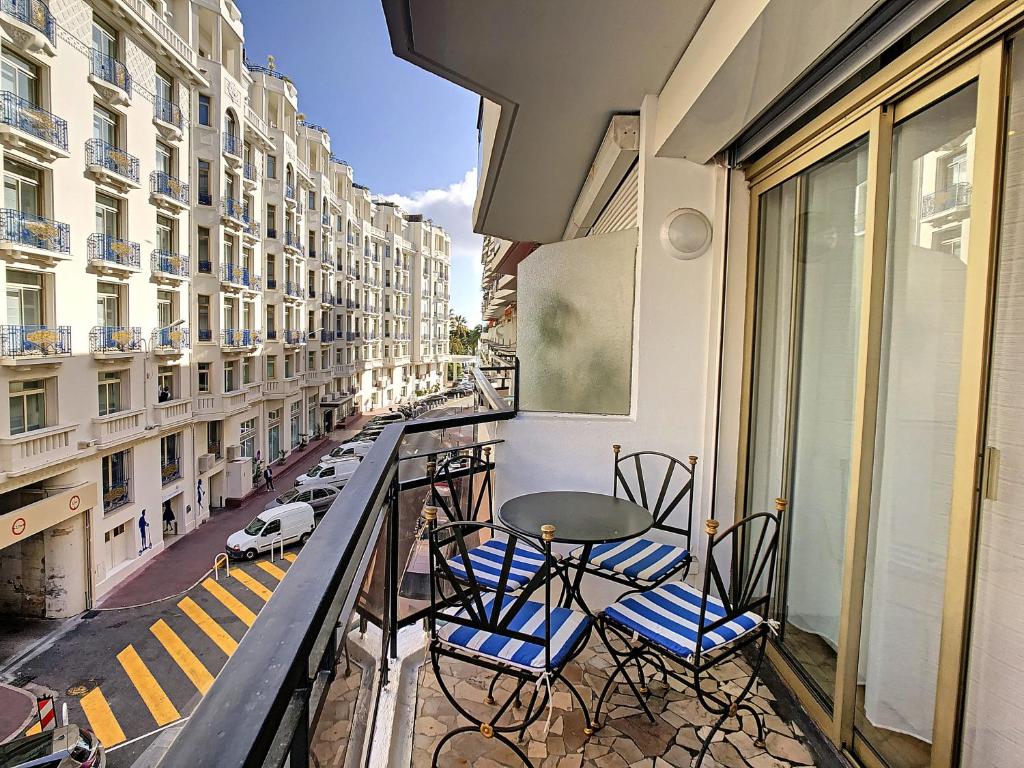 uma varanda com cadeiras, uma mesa e uma rua em Grand studio cabine à côté des plages NER634 em Cannes