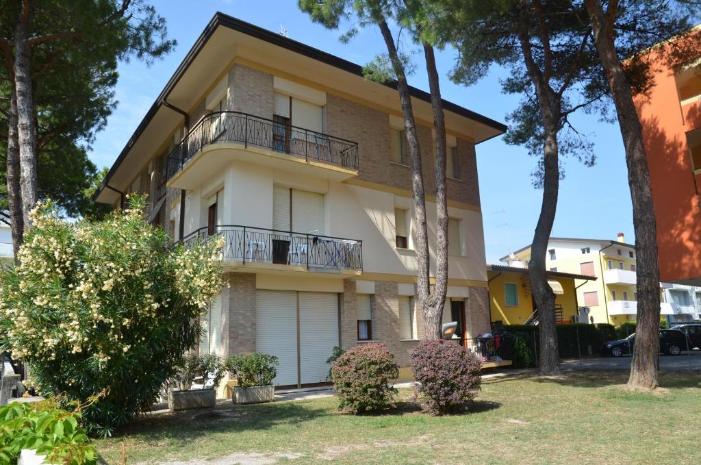 an apartment building with a balcony and trees at Appartamenti Villa Frediana in Bibione