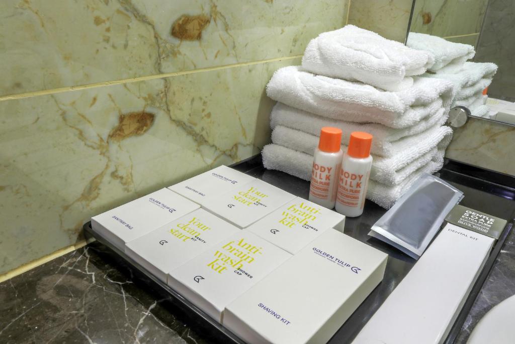 a bathroom counter with towels and products on it at Golden Tulip Westlands Nairobi in Nairobi