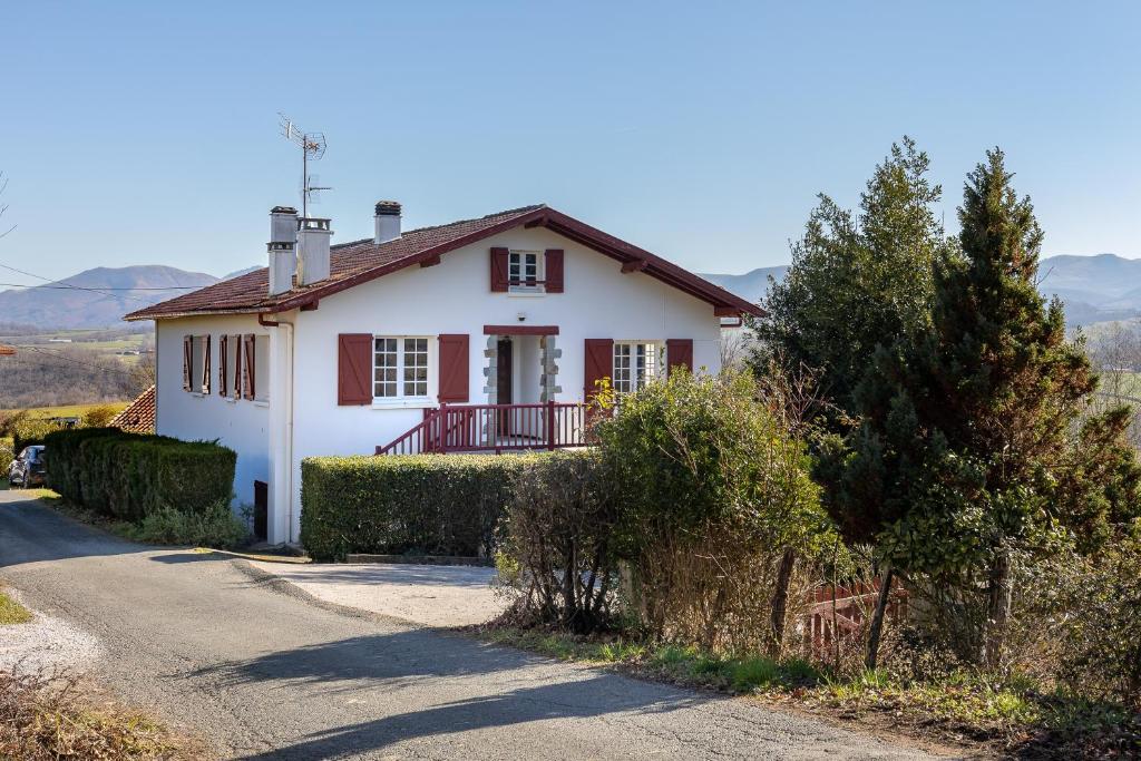 uma casa branca com acabamento vermelho numa estrada em Maison Pikassariko - 4 Chambres proche frontière espagnole em Sare