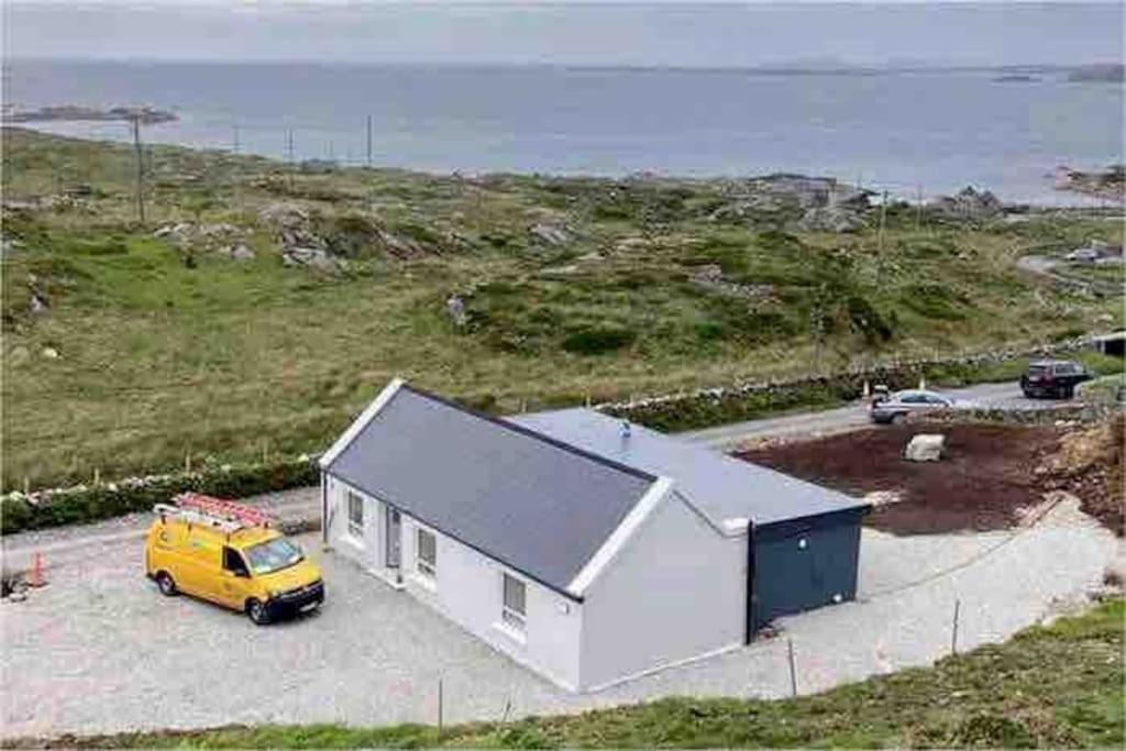 uma carrinha amarela estacionada em frente a uma pequena casa em Mary’s Seaview Clifden em Galway
