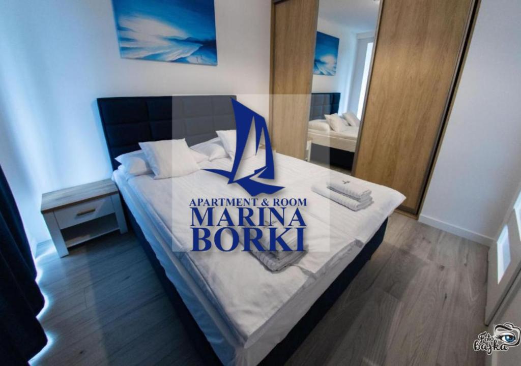 een slaapkamer met een bed met een jachthaven bonka bord erop bij Apartamenty RÓŻA WIATRÓW - MARINA BORKI in Augustów