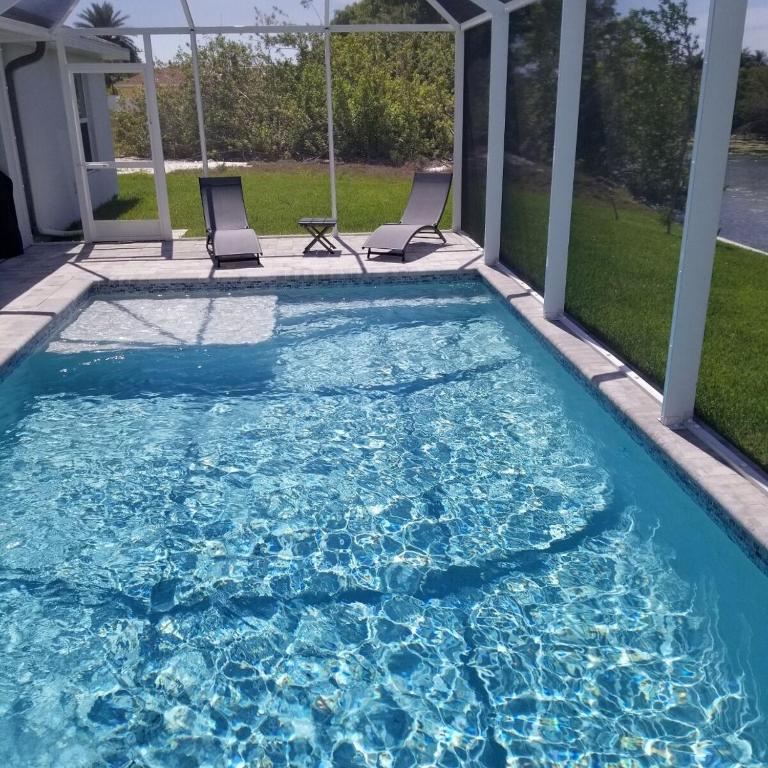 - une piscine avec 2 chaises dans l'eau dans l'établissement Stunning New Home in Cape Coral Florida, à Cape Coral