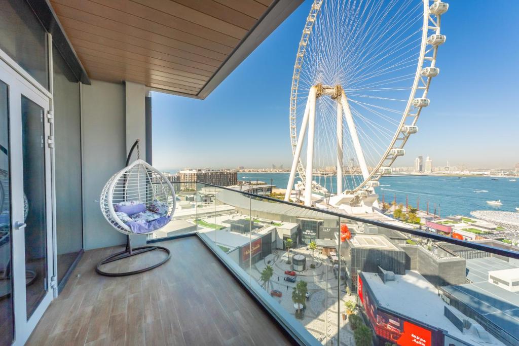 a view of a ferris wheel from a balcony with a chair at FAM Living Bluewaters - Island Living - Ain Dubai & Sea View in Dubai