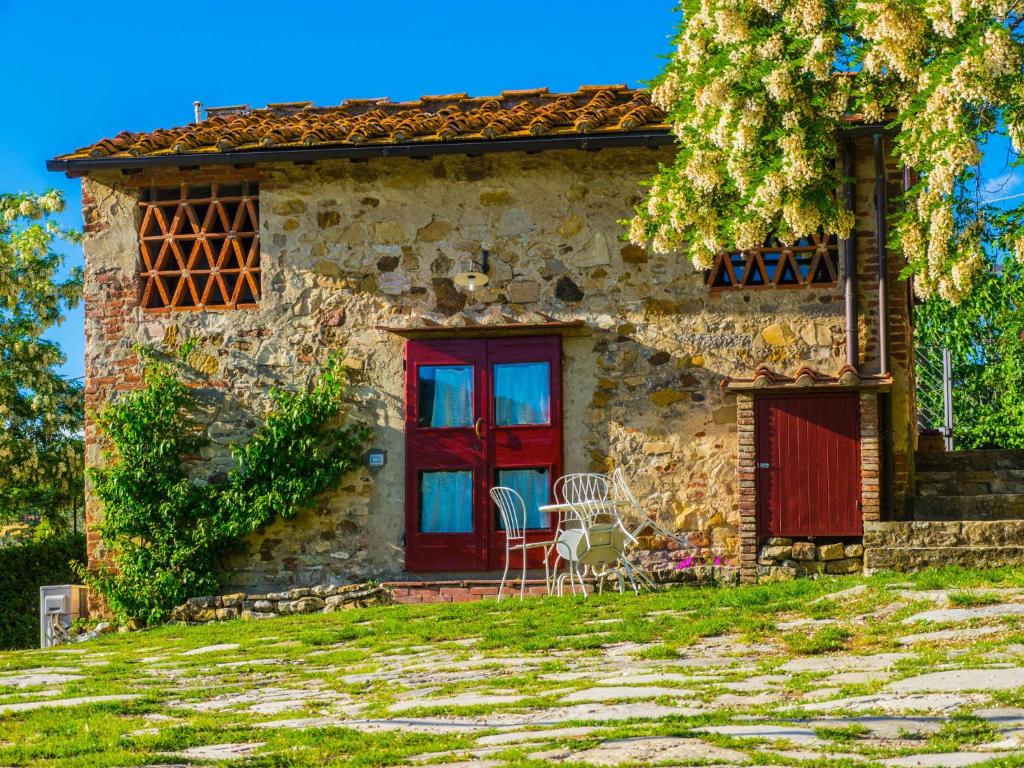 a stone house with a red door and a table at Agriturismo Verde Oliva in Bagno a Ripoli