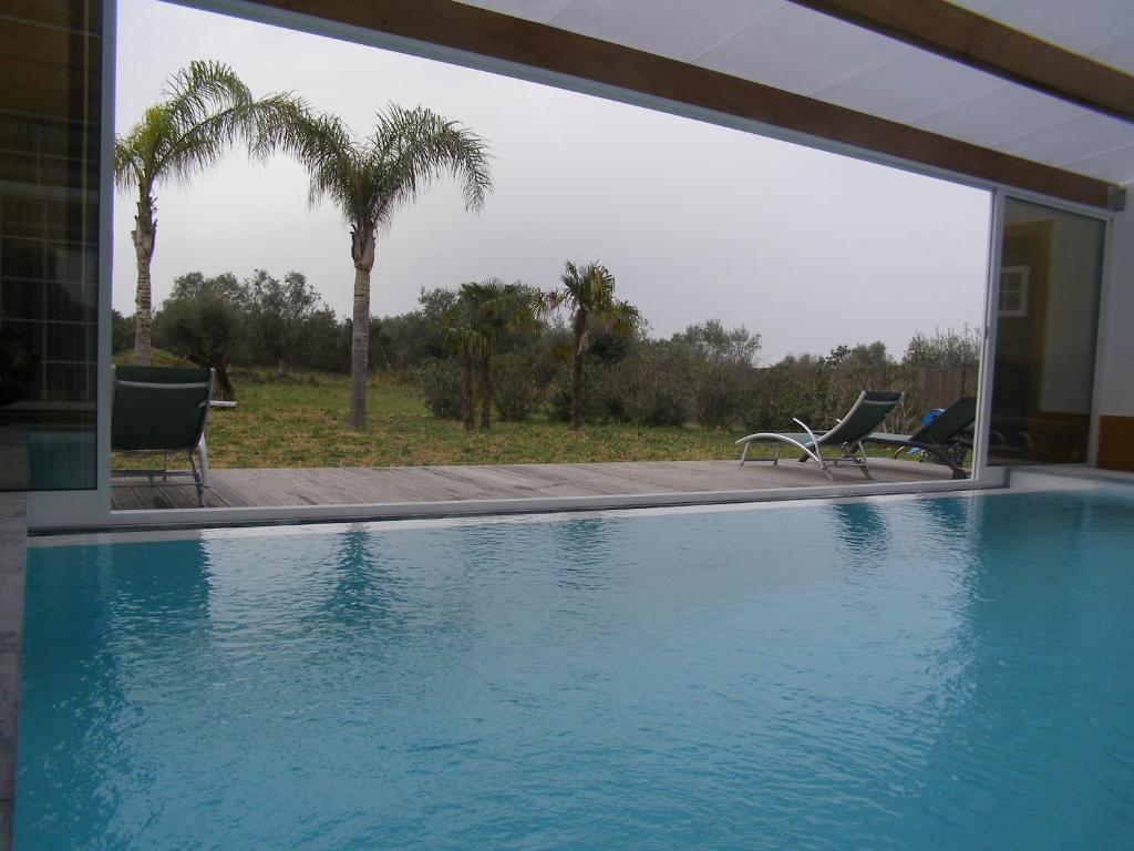 a swimming pool with two chairs and palm trees at Quinta De Azemeis in Vimieiro