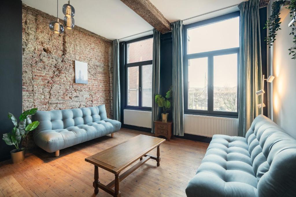 a living room with blue couches and a table and windows at Charming Two-Bedroom River Side Apartment in Antwerp