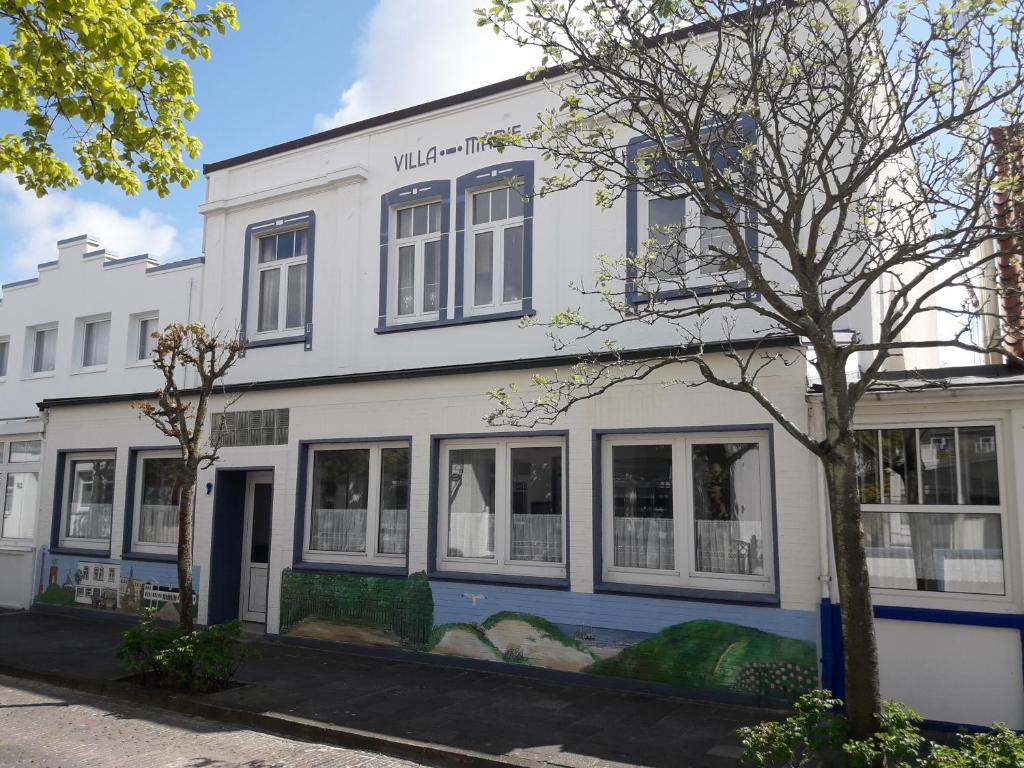 un edificio blanco con ventanas en una calle en Villa Marie Wohnung 1, Norderney en Norderney