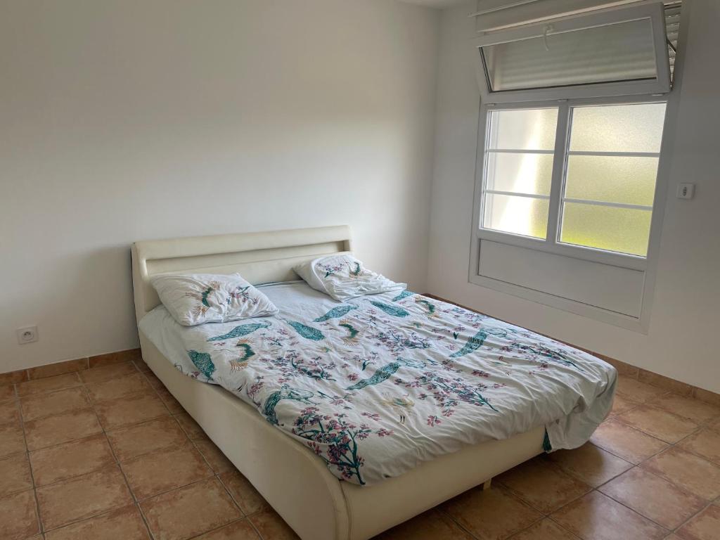 Bett in einem Schlafzimmer mit Fenster in der Unterkunft Piolenc Très bel appartement in Piolenc