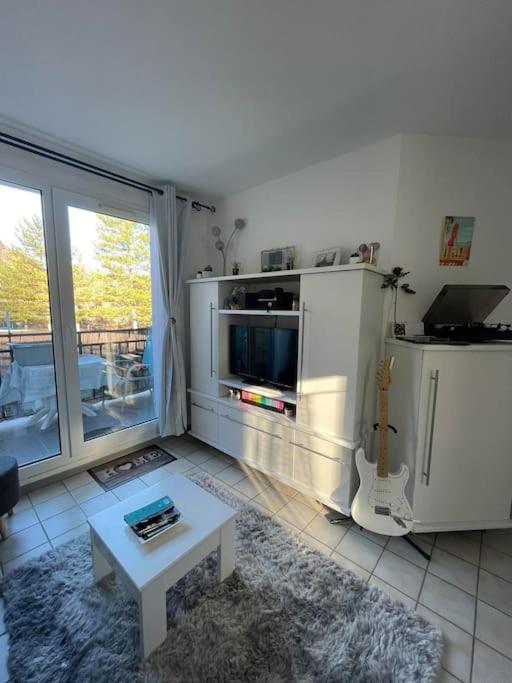 a living room with a tv and a table in it at T2 au cœur de la nature de Digne in Digne-les-Bains