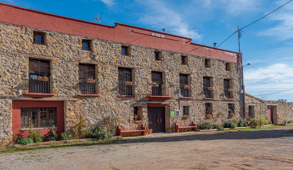 un gran edificio de ladrillo con dos bancos delante en CASA RURAL VICENTA 1750, en Albentosa