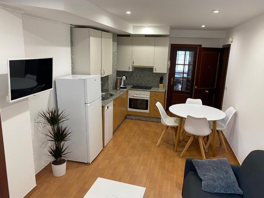 a kitchen with a table and a white refrigerator at SANTA MARTA PLAYA BAIONA in Baiona