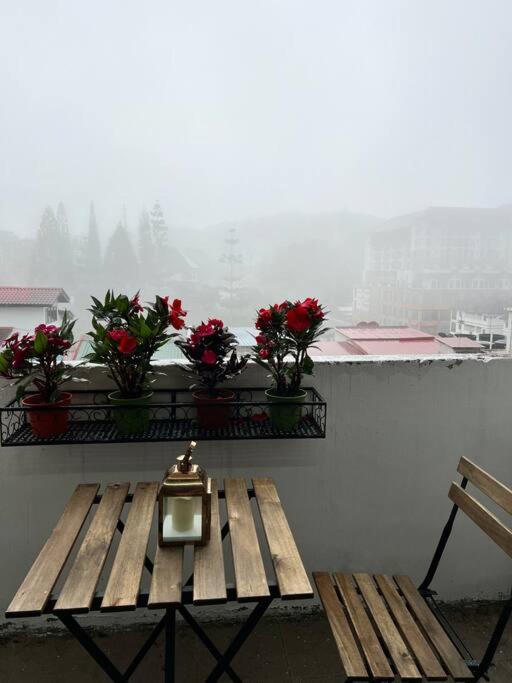 a table with a clock on a balcony with flowers at lily maison in Tanah Rata