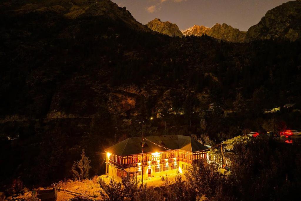 budynek oświetlony nocą z górami w tle w obiekcie Folktales Residency w mieście Saturang
