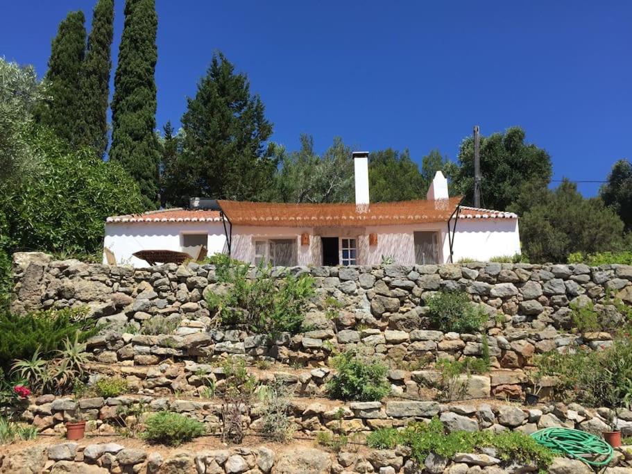 uma pequena casa atrás de uma parede de pedra em Casalinho do Farol em Setúbal