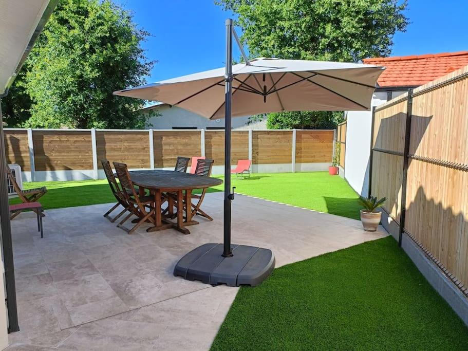 eine Terrasse mit einem Tisch und einem Sonnenschirm in der Unterkunft CHEZ CED - Gujan-Mestras / Bassin d'Arcachon in Gujan-Mestras