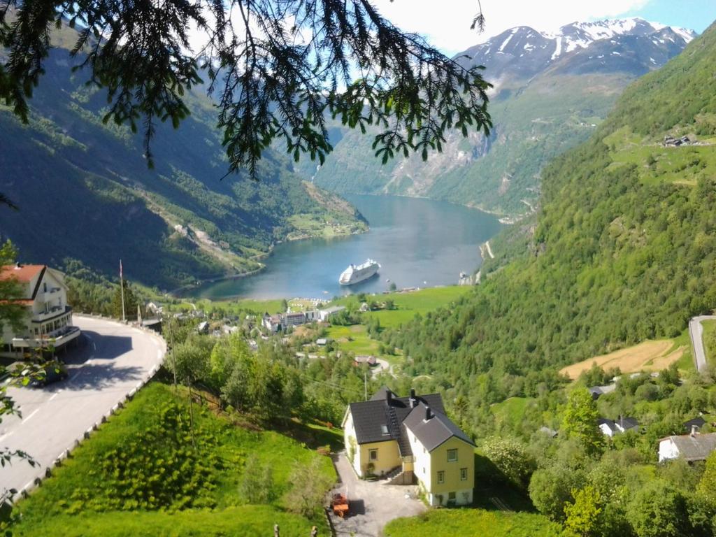 a village in the mountains with a boat in the water at Lunheim in Geiranger in Geiranger