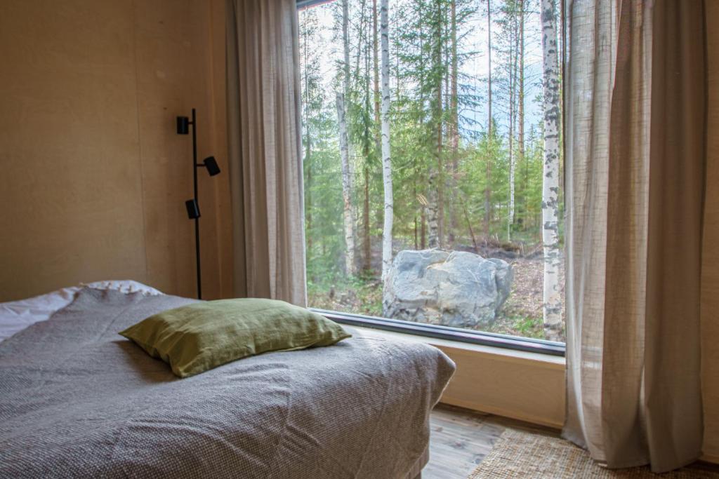 a bedroom with a bed and a window with trees at Venejoen Piilo - Naava in Romppala