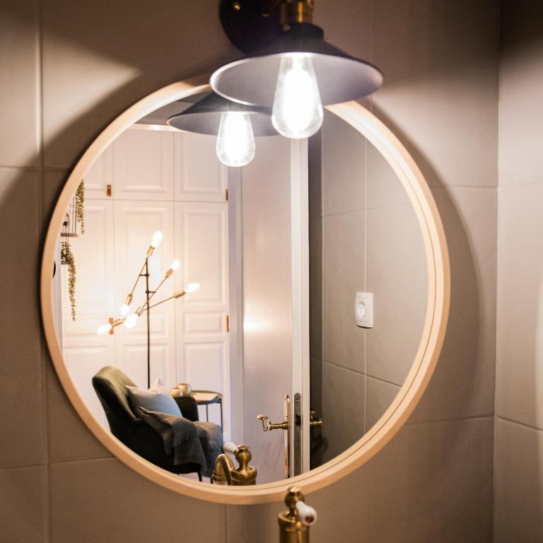 einen Spiegel im Bad mit Stuhl und Lampe in der Unterkunft Privatzimmer - Sieben an der Donau in Ottensheim