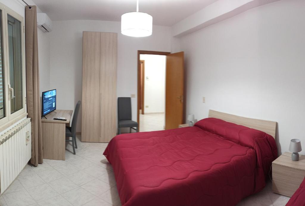 een slaapkamer met een rood bed en een bureau bij Contessa Vacanze Byron in Contessa Entellina