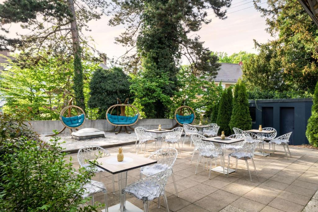 a patio with tables and chairs and trees at Arthotel ANA Gold in Augsburg