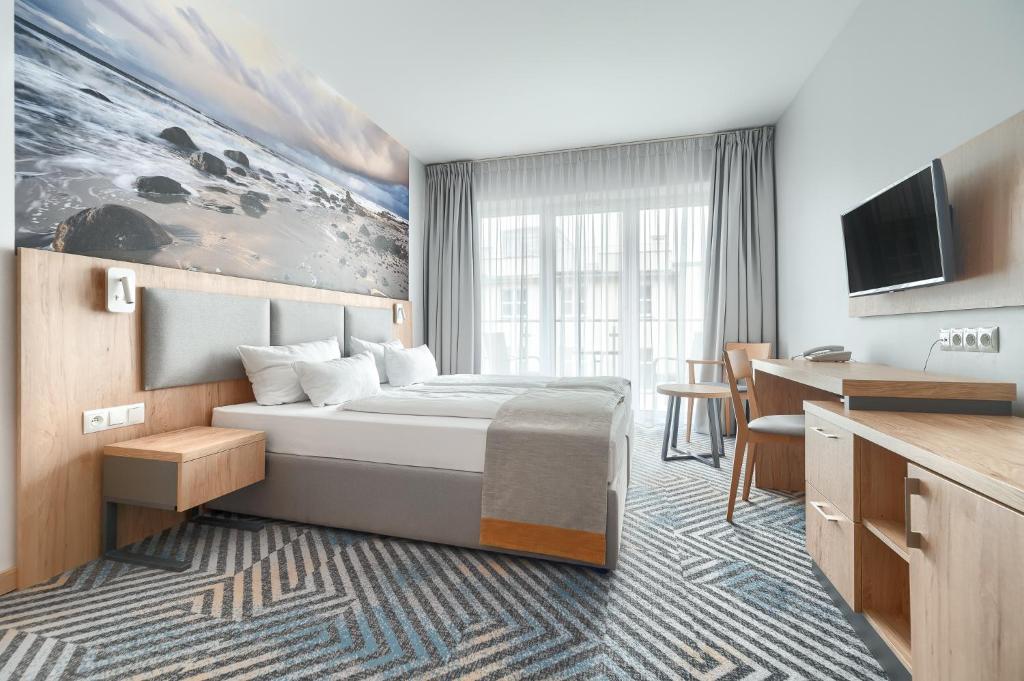 シフィノウイシチェにあるAfrodyta Spaのベッドとデスクが備わるホテルルームです。