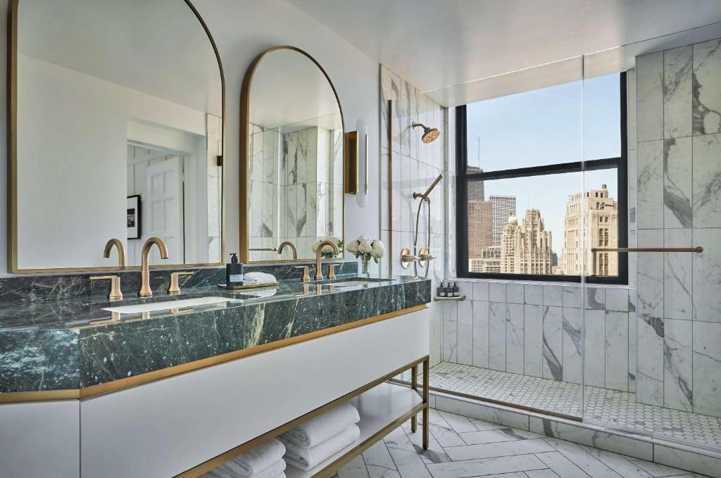 uma casa de banho com um grande lavatório em mármore e uma janela em Pendry Chicago em Chicago