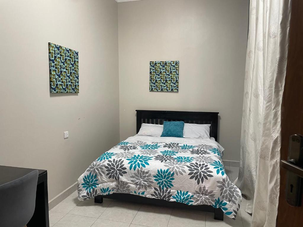 a bedroom with a bed and two pictures on the wall at Boston Apartments Dodoma in Dodoma