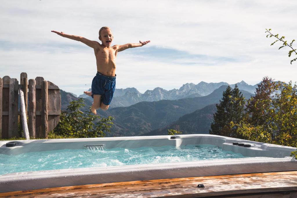 a man jumping into a jacuzzi tub in the mountains at Obiralmhütte Meierhof in Bad Eisenkappel