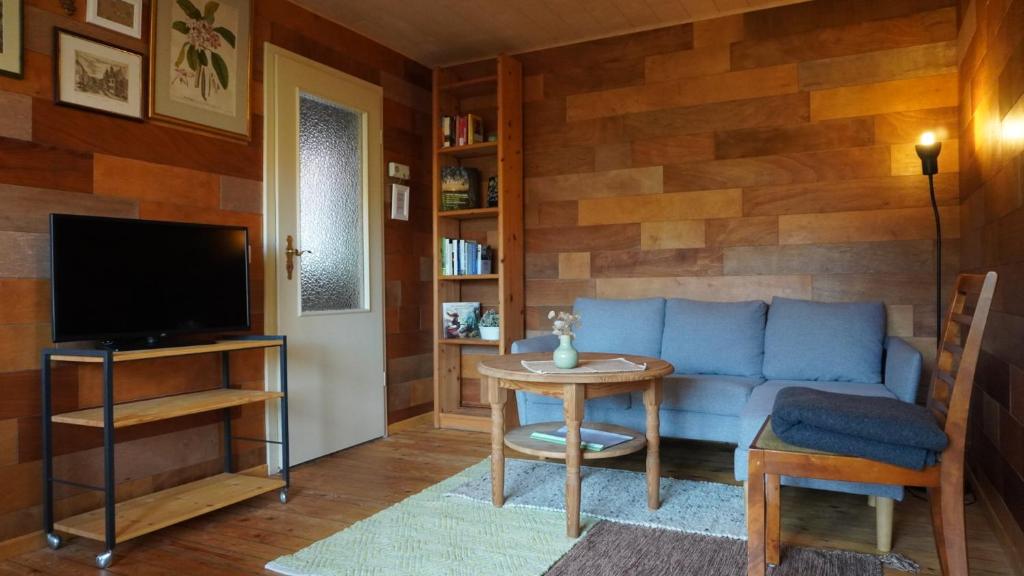 ein Wohnzimmer mit einem blauen Sofa und einem Tisch in der Unterkunft Hütte mit Herz im Harz in Meisdorf