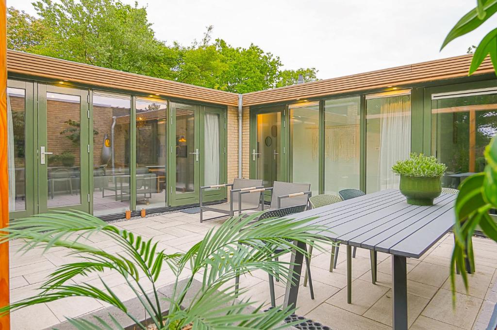 un patio cerrado con mesa de madera y sillas en Diva in de Duinen - Park Duinland Sint Maartenszee, en Sint Maartensvlotbrug