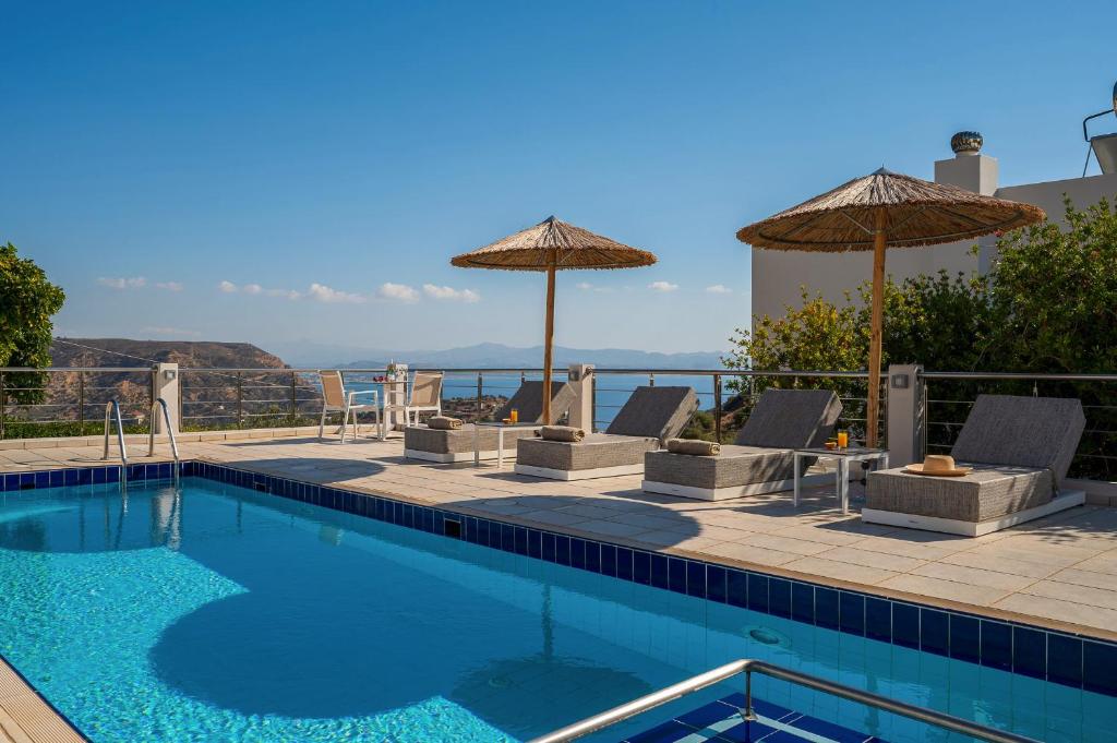 a swimming pool with chairs and umbrellas at Lenikos Resort in Agia Galini
