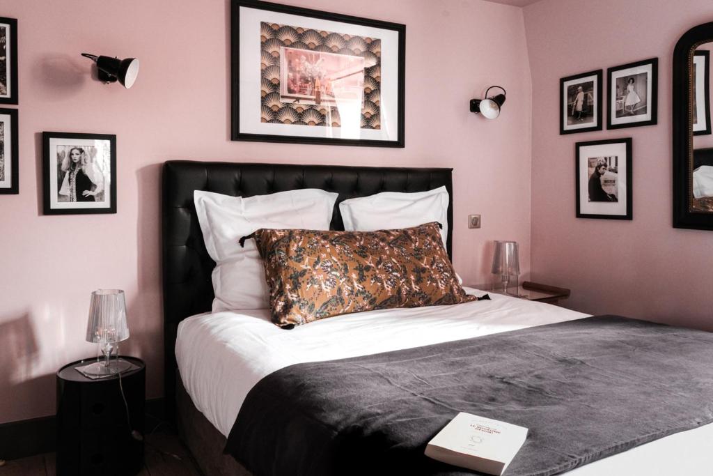 - une chambre avec un grand lit et des photos sur le mur dans l'établissement La Femme d'à Côté, à Saint-Valery-sur-Somme