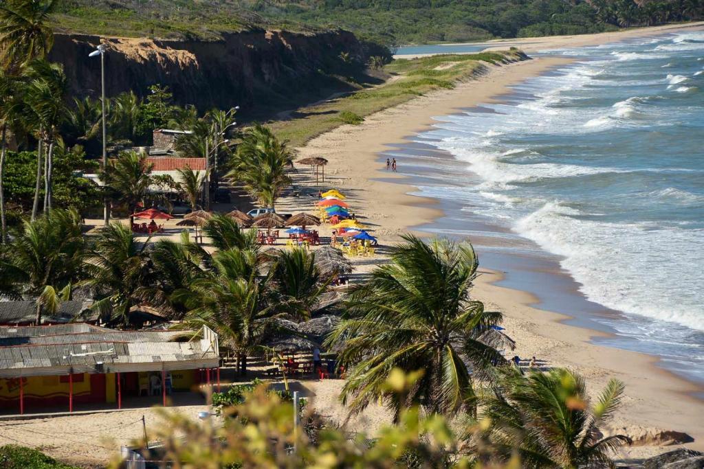 einen Strand mit Palmen und Sonnenschirmen und dem Meer in der Unterkunft Casa do Léo 1 - Temática México e África in João Pessoa