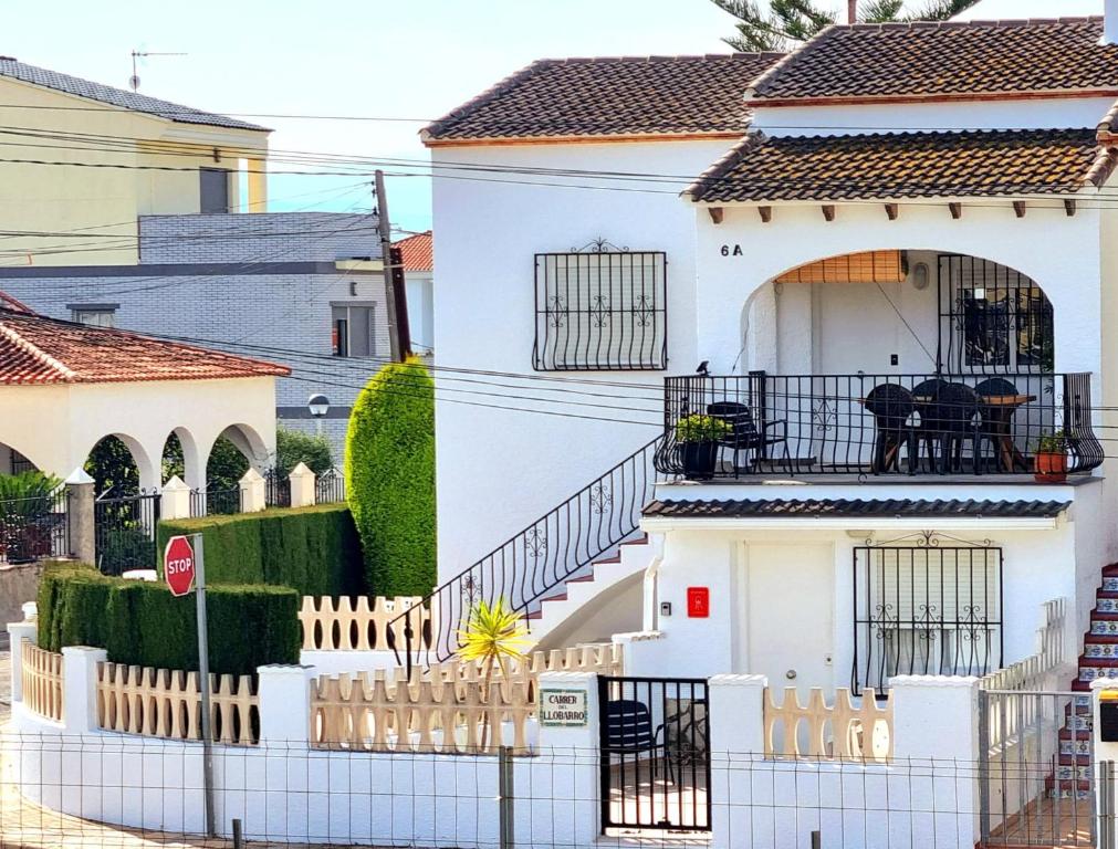 una casa blanca con una valla delante en HELLO OLIVA BEACH Bungalow Bajo, en Oliva