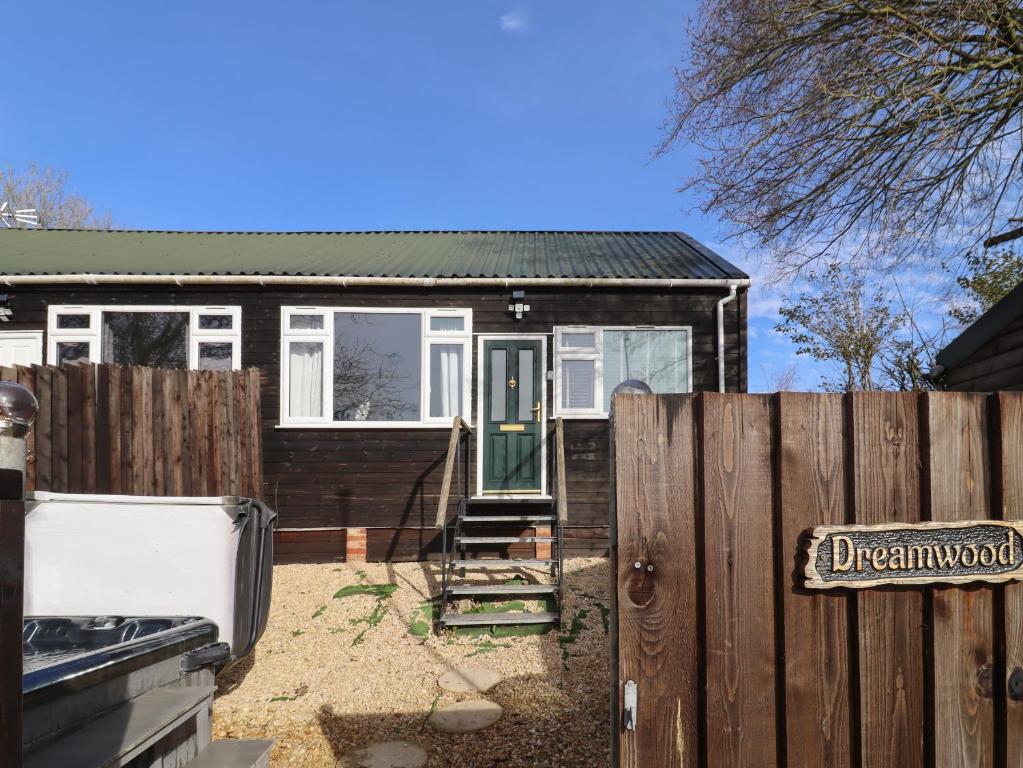 a small house behind a fence with a gate at Dreamwood in Blandford Forum