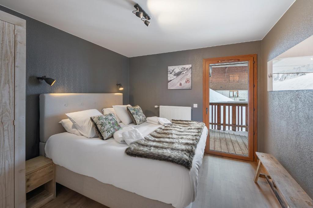 ein Schlafzimmer mit einem großen weißen Bett und einem Fenster in der Unterkunft Les Loges Blanches - Apt C001 - BO Immobilier in Châtel