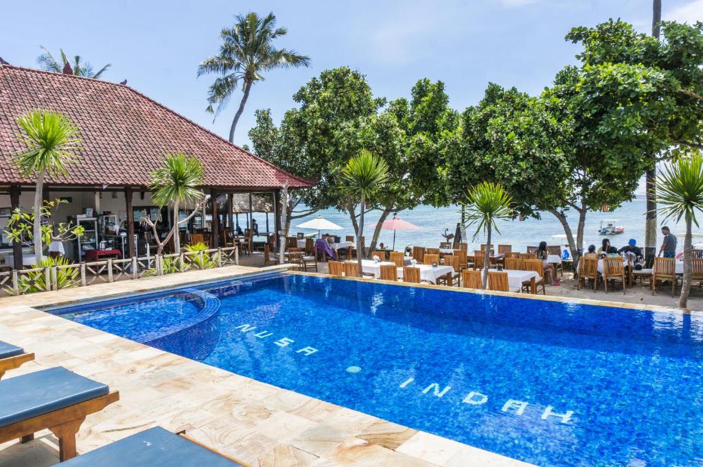 een zwembad in een resort met tafels en stoelen bij Nusa Indah Bungalow in Nusa Lembongan