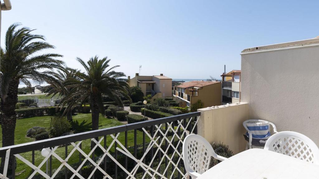 un balcon avec une table, des chaises et des palmiers dans l'établissement Aquaplage- 230- Appart vue mer- 6 pers, au Cap d'Agde