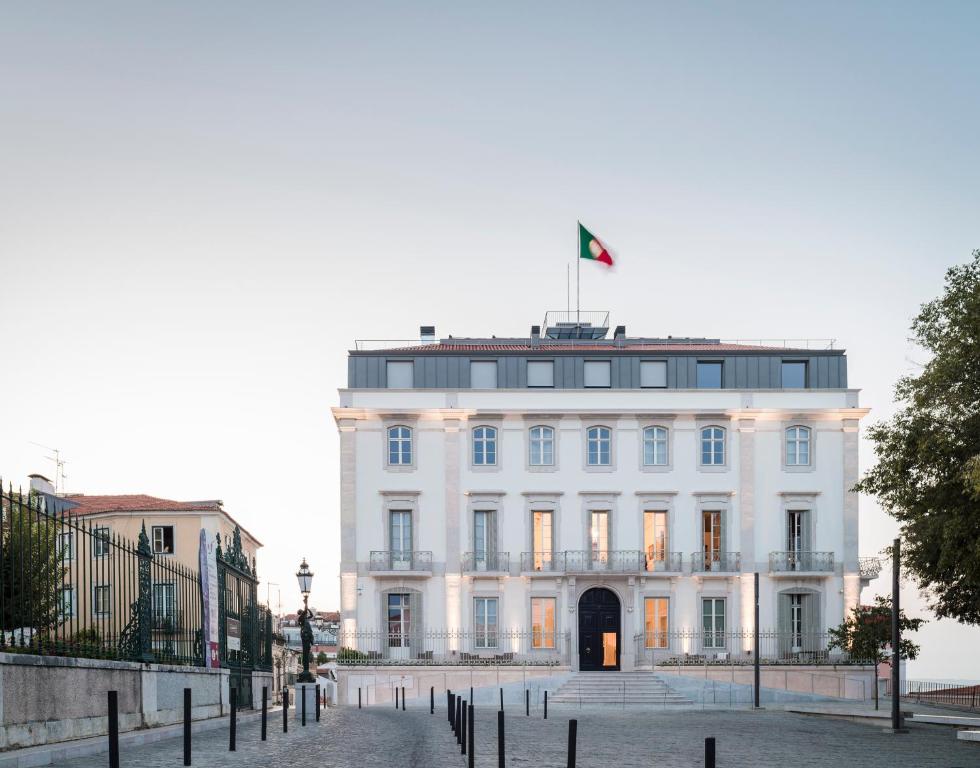a white building with a flag on top of it at Verride Palácio Santa Catarina in Lisbon