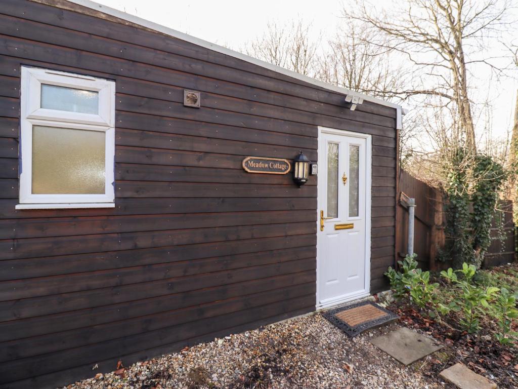 una casa negra con una puerta blanca y una ventana en Meadow en Blandford Forum