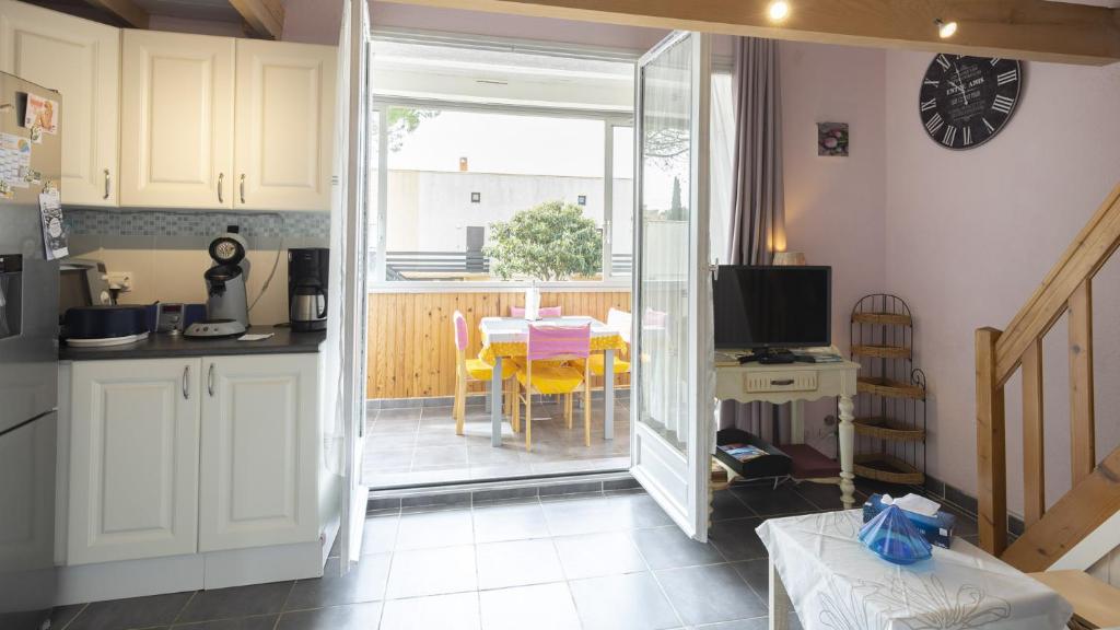 une cuisine et une salle à manger avec une table et des chaises jaunes dans l'établissement Les Estivales- 9H- Studio charme- 4 pers, au Cap d'Agde
