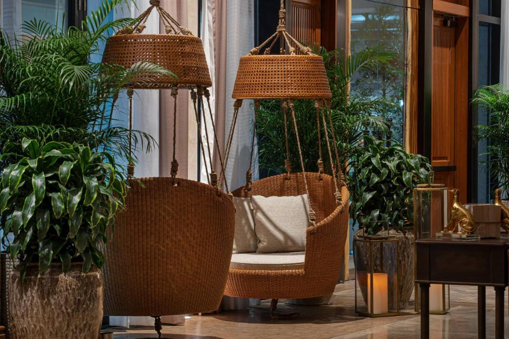 a porch with two swinging chairs and potted plants at The Ben, Autograph Collection in West Palm Beach