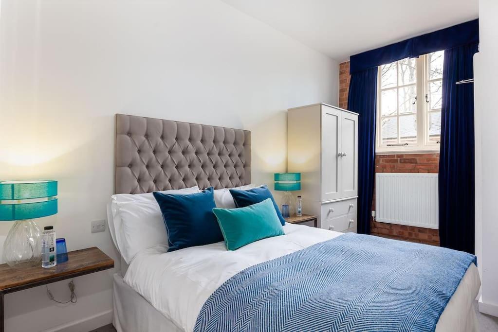 um quarto com uma cama grande e almofadas azuis em Bowen-Buscarlet (Large Suite) at Bicester Heritage em Bicester