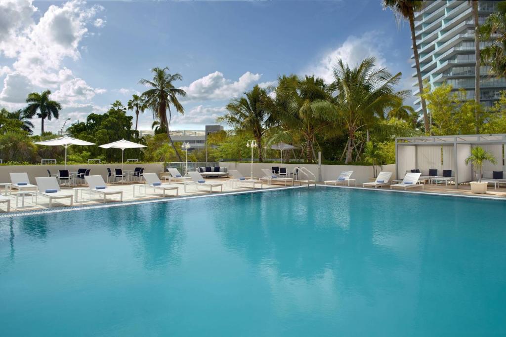 una gran piscina con sillas y sombrillas en Courtyard Miami Coconut Grove, en Miami