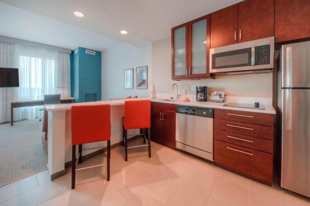 una cocina con armarios de madera y sillas rojas. en Residence Inn by Marriott Raleigh Downtown en Raleigh