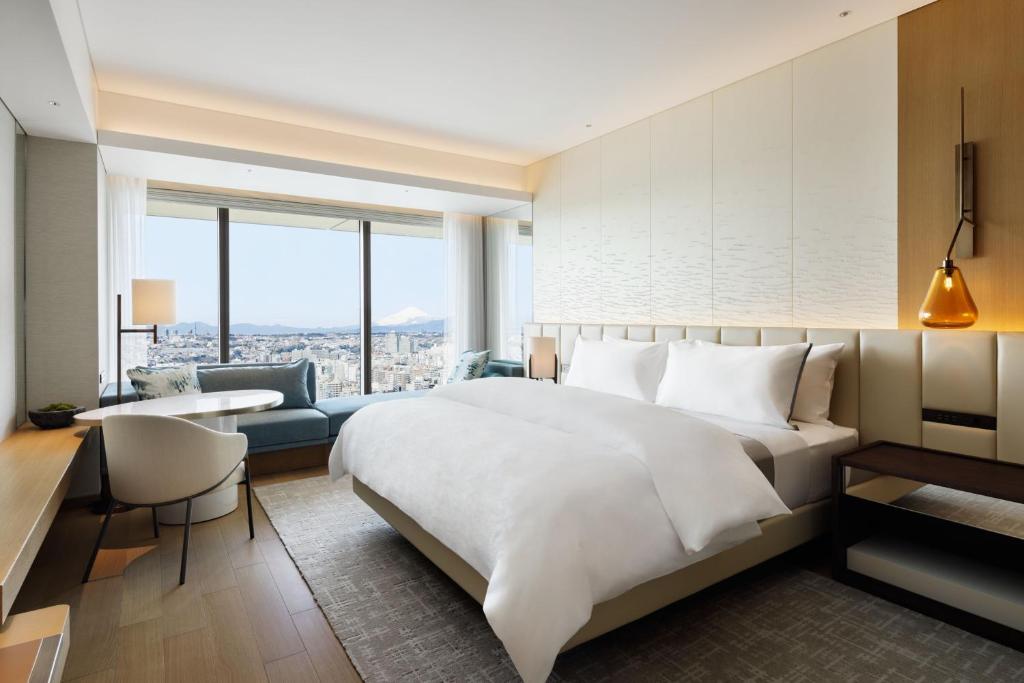 een slaapkamer met een groot wit bed, een bureau en een bank bij The Westin Yokohama in Yokohama