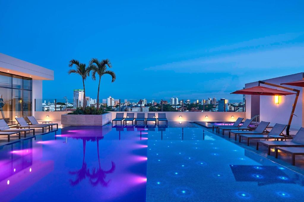 a pool with chairs and a city skyline at night at Marriott Santa Cruz de la Sierra Hotel in Santa Cruz de la Sierra