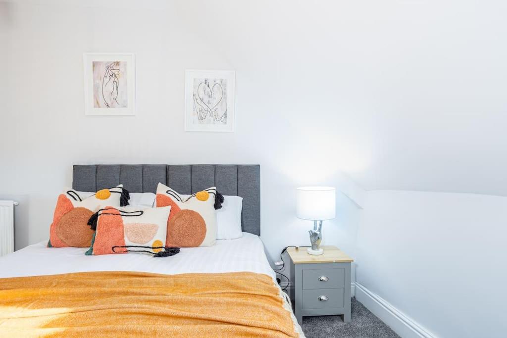 a bedroom with a bed with orange and white pillows at Beautiful newly refurbished apartment close to the promenade. in Llandudno